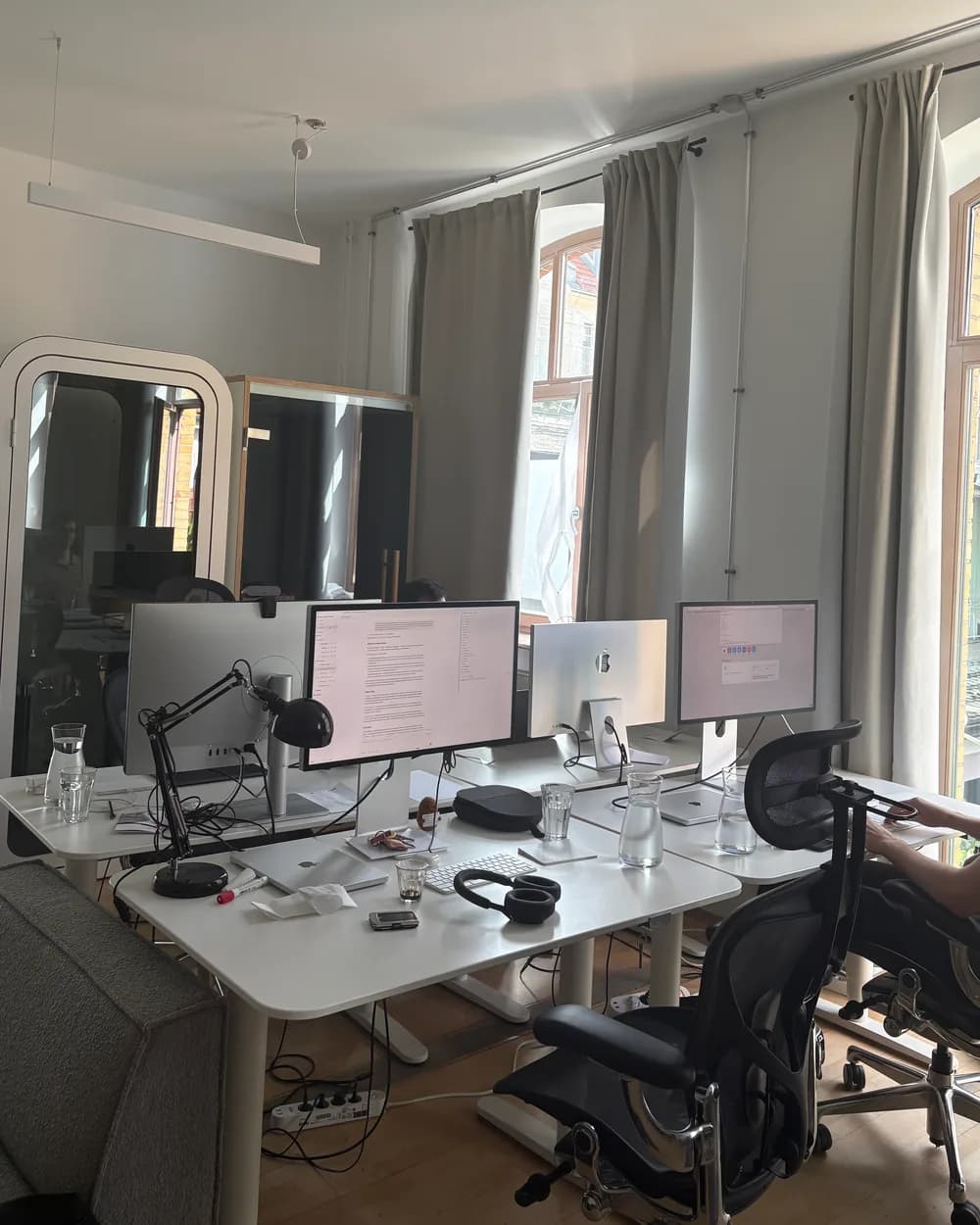Our desks in the Berlin office: four monitors, a phone booth and tall windows onto the street